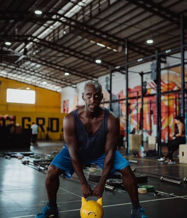 Focused man holding a kettlebell during a workout session in a minimalist setting.